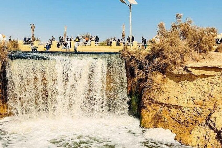A waterfall with people standing on a viewing platform. 1