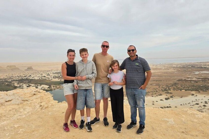 A group of people standing on a sandy terrain with a desert landscape in the background. 4