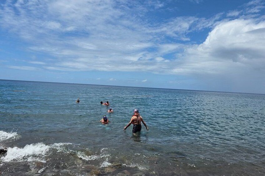 A beach with people swimming and walking in the water. 4