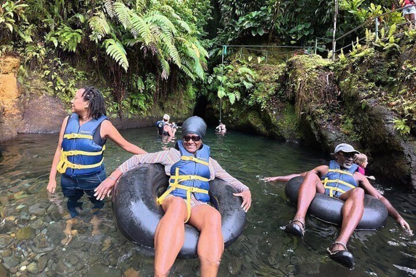 People floating on tubes in a natural water setting surrounded by greenery. 2