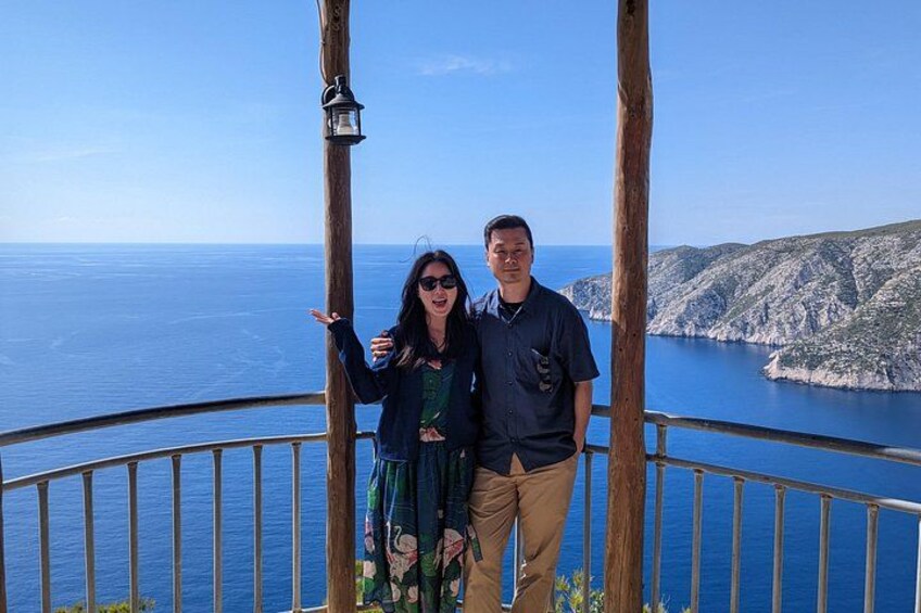 Una coppia in piedi su un balcone con vista su un paesaggio costiero, scogliere e mare. 5