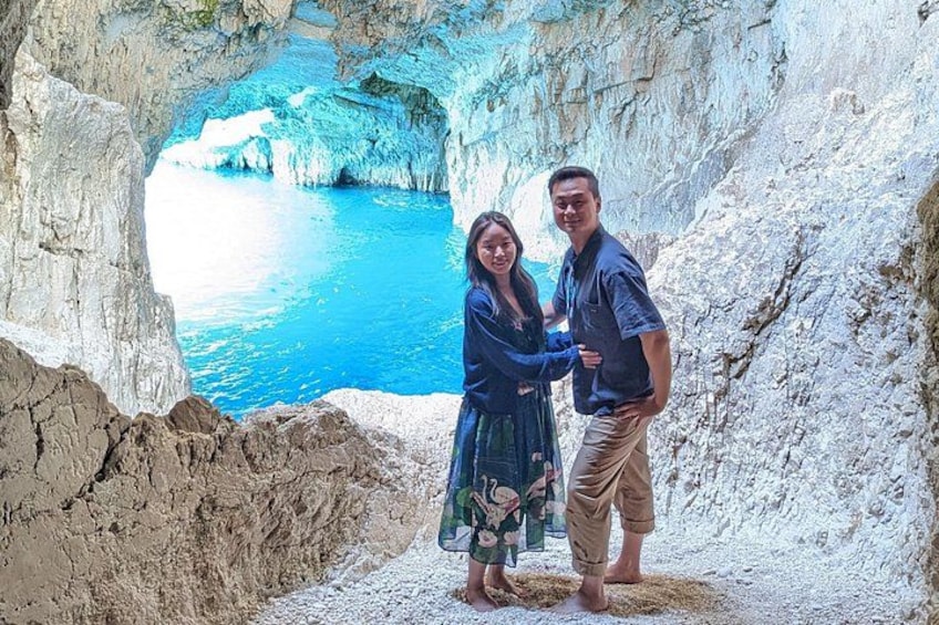 Ein Paar steht in einer felsigen Höhle, durch den Eingang ist ein blaues Meer zu sehen. 5