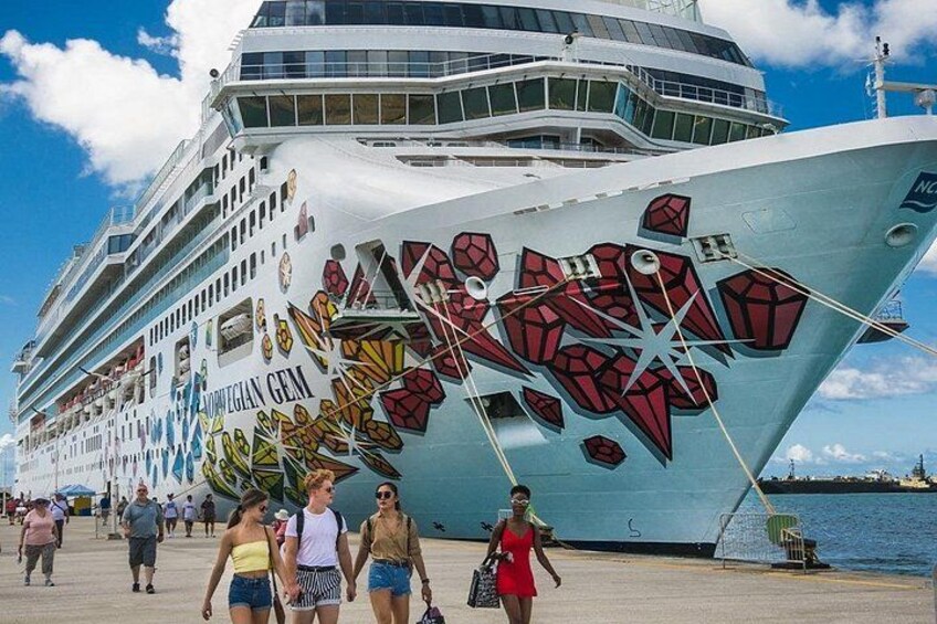 A cruise ship with a colorful bow design and the name 'Norwegian Gem' visible. 1
