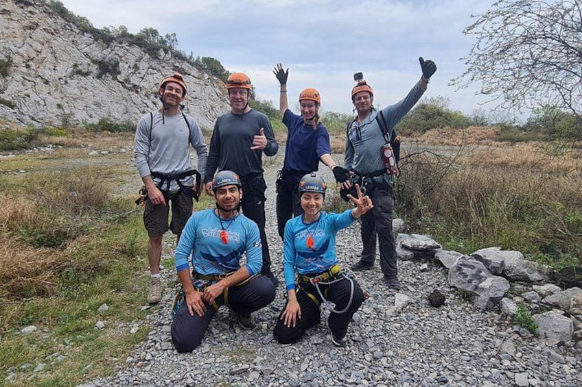 En gruppe mennesker i outdoor-tøj poserer på et klippefyldt område med et bjerglandskab i baggrunden. 3