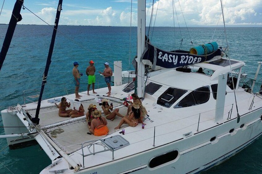Un velero con gente en la cubierta, un cartel que dice 'EASY RIDER' y el océano al fondo. 3