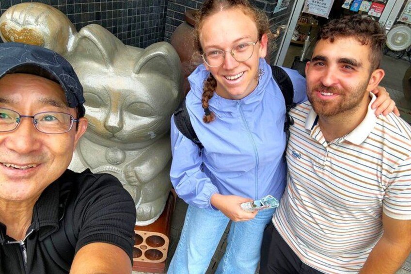 Three people posing in front of a sculpture. 1