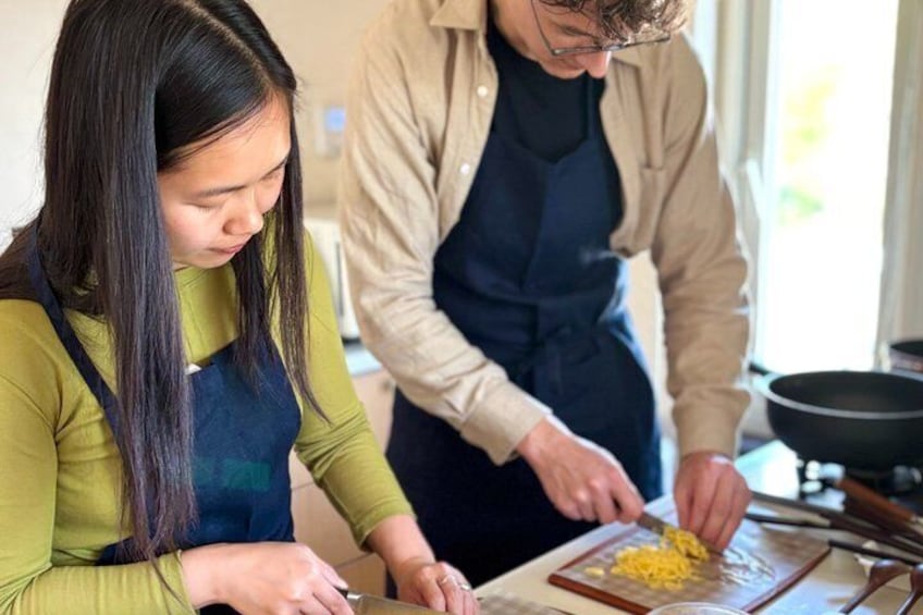 Deux personnes sont en train de cuisiner : l’une râpe du fromage et l’autre prépare les ingrédients sur une planche à découper. 5