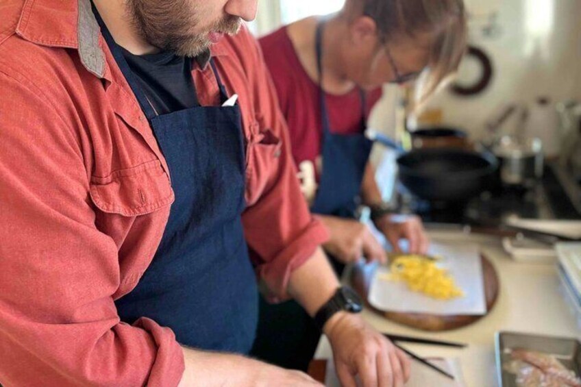 A person wearing a red shirt and blue apron, preparing food at a kitchen counter. 4