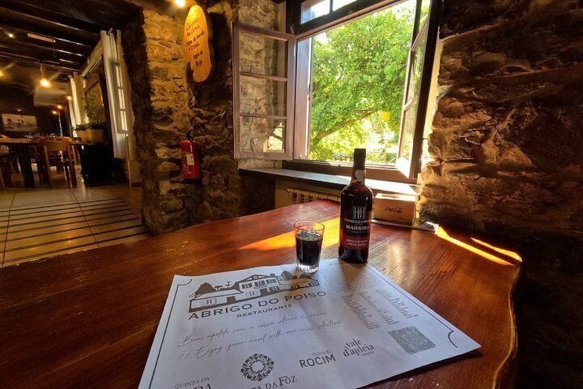 A wooden table with a menu, a bottle of wine, and a glass of wine in a rustic restaurant setting. 3