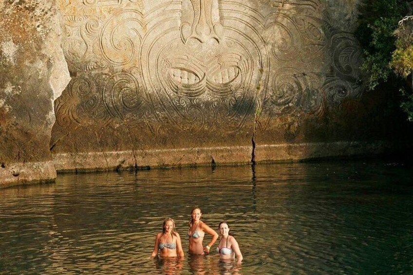 Une grotte ornée de sculptures complexes, une étendue d’eau et deux personnes dans l’eau. 2