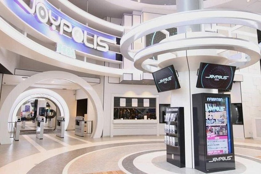 Interior moderno de un centro comercial con un diseño circular central, varios niveles y pantallas digitales informativas. 4