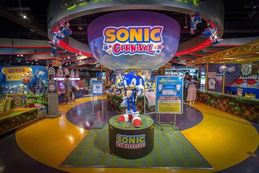 Un parque de atracciones cubierto con una estatua de Sonic el Erizo, varios juegos de arcade y decoraciones coloridas. 3