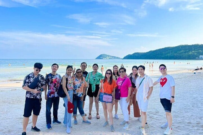 Un grupo de personas en la playa con el océano y una colina distante al fondo. 4