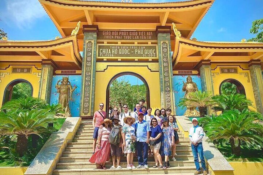 Un grupo de personas en la entrada de un templo, con una gran estatua de Buda y un cartel con texto. 3