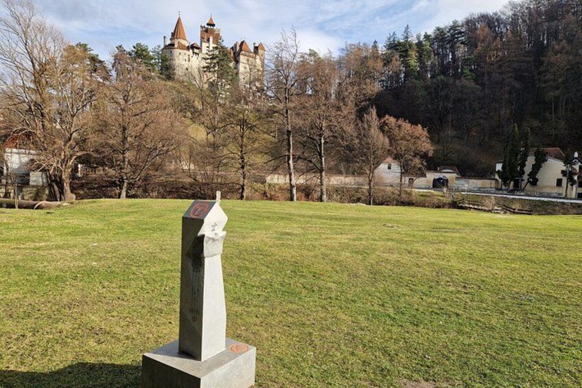 A grassy field with a stone monument in the foreground and a castle in the background. 4