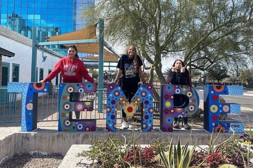 Three people standing in front of colorful, circular letter-shaped structures. 2