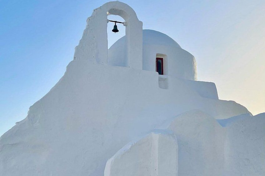 A white building with a bell tower and a small window. 2