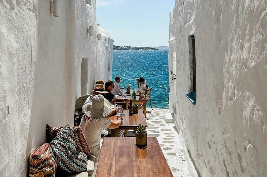 Ein schmaler Gang mit weißen Wänden, einem Holztisch und Blick auf das Meer. 5
