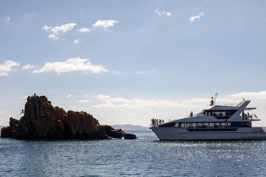 A boat on calm water, a rocky outcrop, and a clear sky. 3