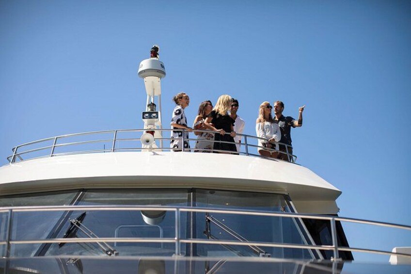 A group of people on a boat's deck, a lighthouse, and a clear blue sky. 4