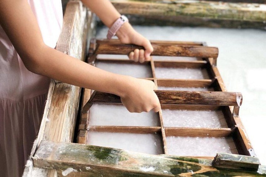 A person handling a wooden grid structure over a body of water. 2