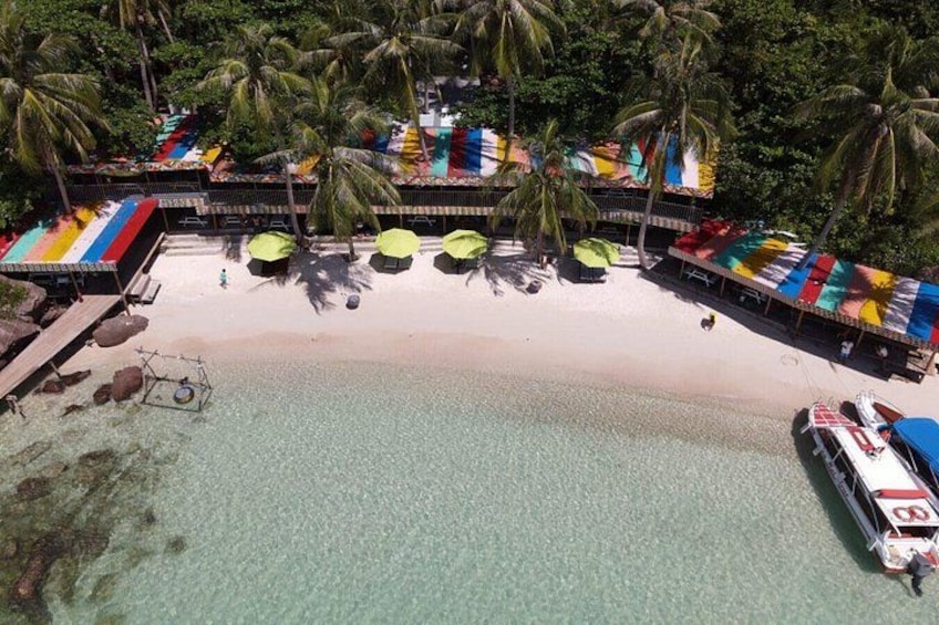 A beach with a resort, palm trees, and a boat. 5