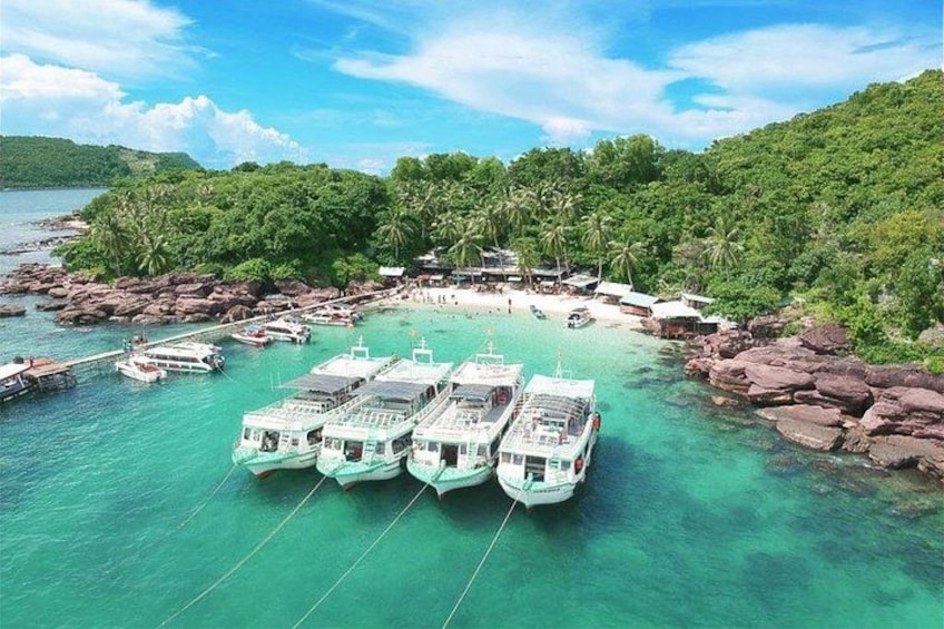 A boat docked at a pier surrounded by clear turquoise water and lush greenery. 4