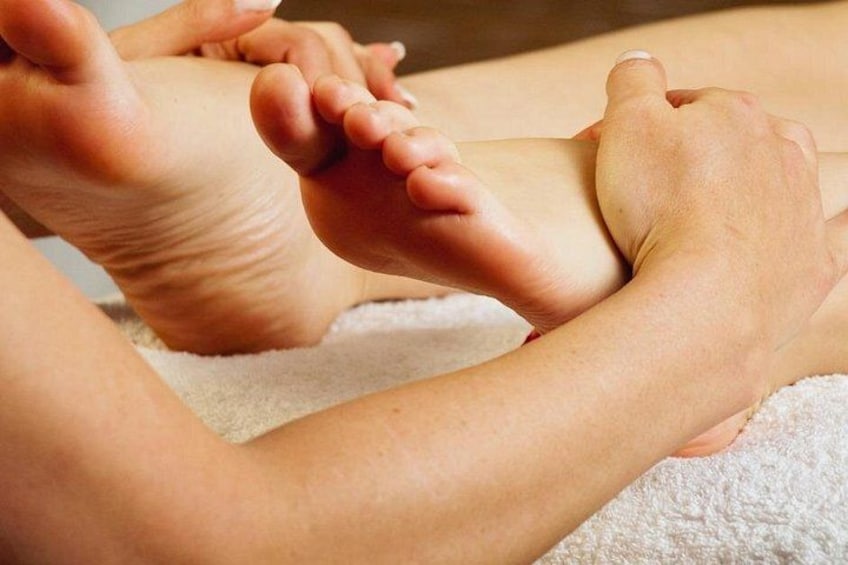 Voetmassage met handen op een voet, op een witte handdoek. 2