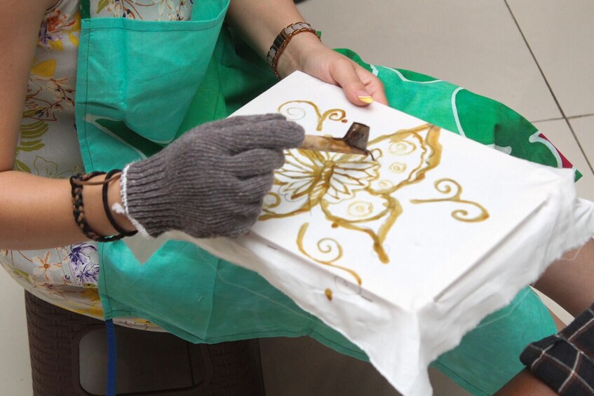 Una persona dibujando un diseño floral sobre una superficie blanca con un bolígrafo. 1