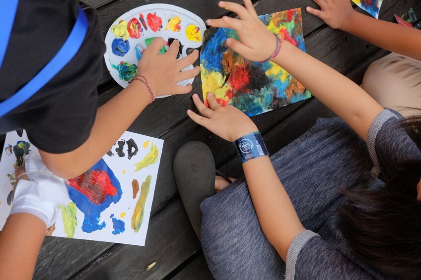 Niños pintando sobre papel con una paleta de colores. 3