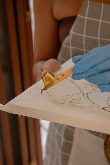 Una persona pintando un diseño floral sobre un lienzo. 5