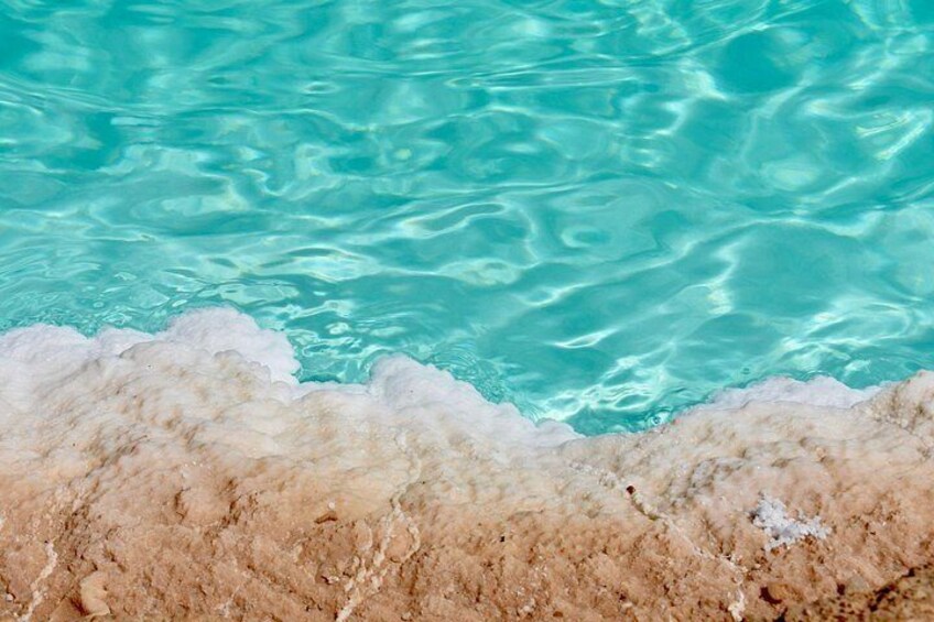 Clear turquoise water, a sandy beach, and a rocky shoreline. 2