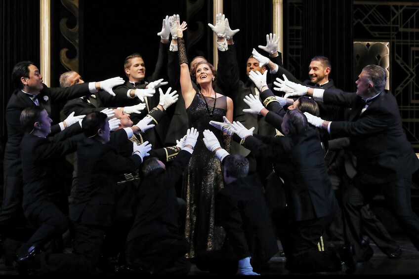 A woman in a black dress surrounded by men in black suits and white gloves. 4