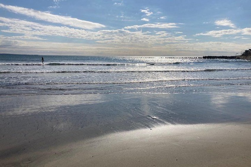 Une plage avec des vagues, une personne qui se promène et un ciel nuageux. 1