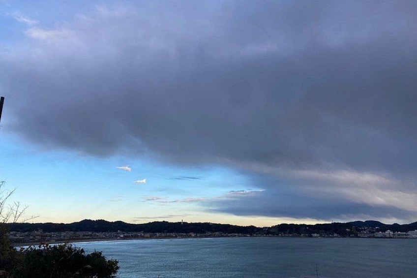 Un paysage côtier avec une étendue d’eau, des collines lointaines et un ciel nuageux. 5