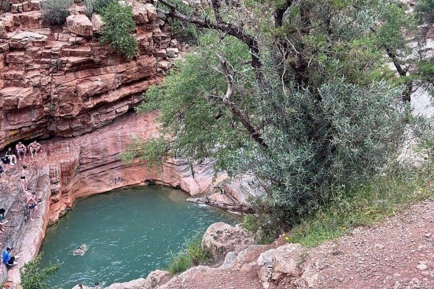 Una piscina natural rodeada de acantilados rocosos y vegetación escasa. 4