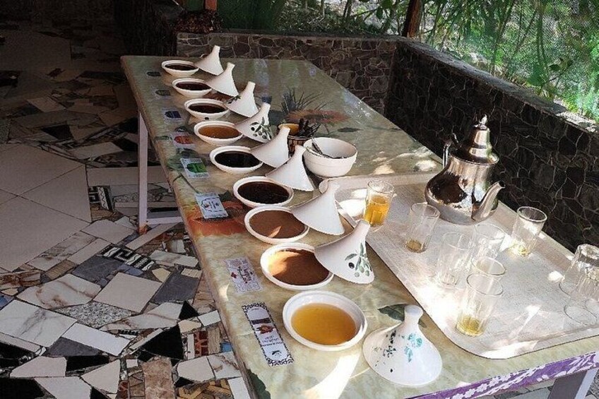 Una larga mesa con varios recipientes de té y café, una tetera y vasos. 3