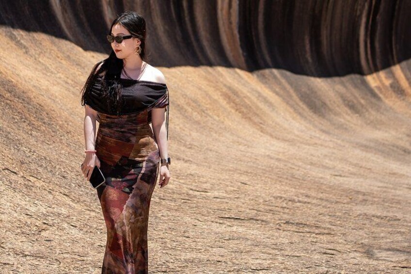Una persona caminando por un desierto, vestida con un vestido estampado y sosteniendo un teléfono. 2