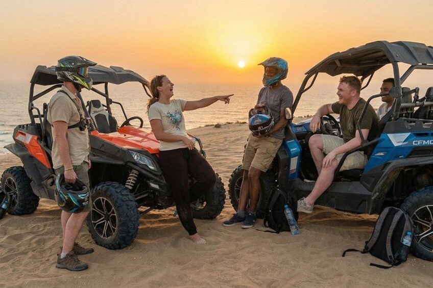 Cuatro personas manejando vehículos todo terreno en una playa al atardecer. 2