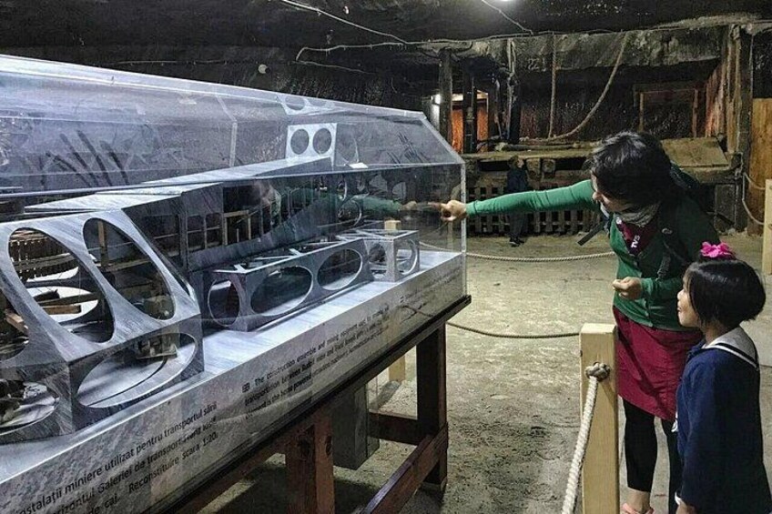 A person pointing at a transparent display case with a car model inside. 3