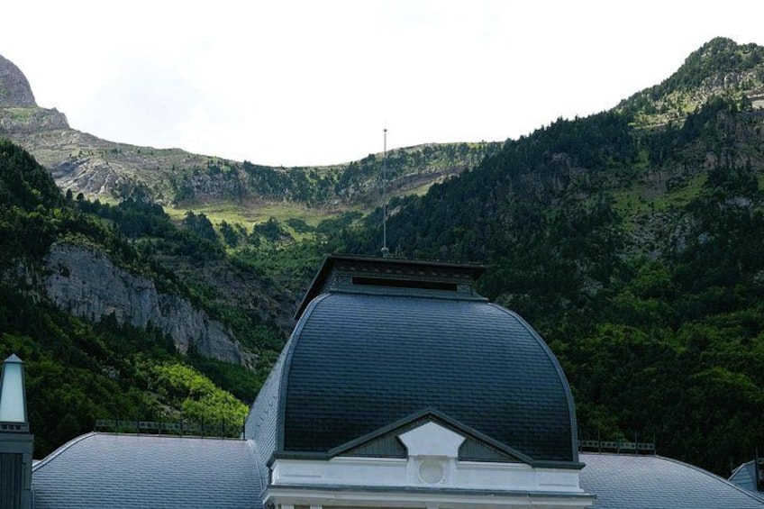 Una casa con un tetto curvo e un camino, sullo sfondo di montagne. 2