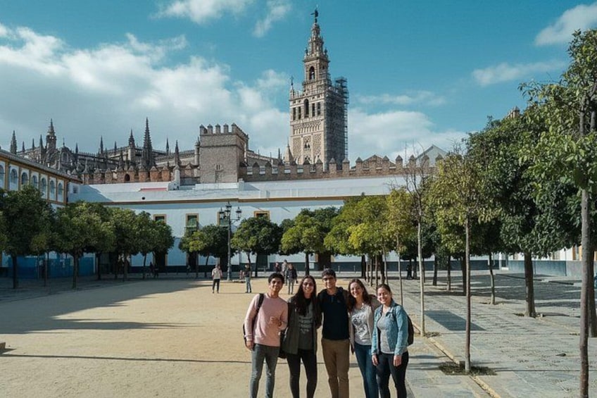 A group of people standing in a plaza with a historic building and a tower in the background. 5
