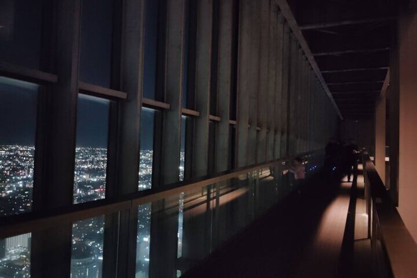 Vista nocturna desde un edificio alto con ventanas amplias que dan a un paisaje urbano. 3