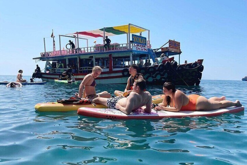 Personas sobre tablas de surf en el agua, con un barco al fondo. 5