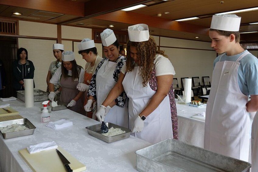 Un grupo de personas en una cocina, con gorros de chef y delantales, preparando comida. 2
