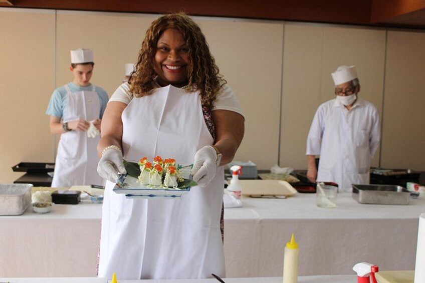 Una persona con uniforme blanco de chef sostiene una bandeja con alimentos. 4