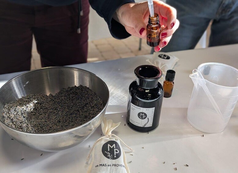 A person pouring a liquid from a dropper into a small bottle labeled 'LAVANDIN BIO'. 5