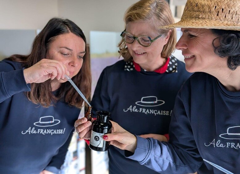 Three people wearing matching 'Ala Française!' t-shirts, holding a bottle labeled 'Mandelin BIO'. 1
