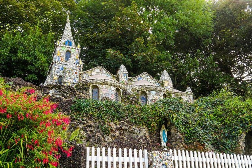 A colorful mosaic church with a white picket fence in front. 2