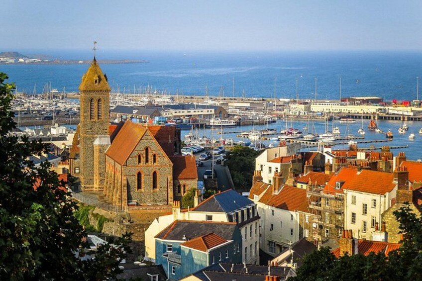 A coastal town with a prominent church, a marina with boats, and a hilly backdrop. 4
